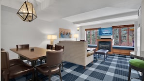 A hotel room with a dining area, a fireplace, and a television.