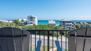 A balcony with two chairs overlooking a coastal view with houses and the ocean.