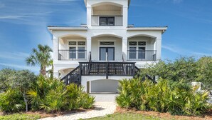 A two-story house with a balcony, a front door, and a staircase leading to the entrance.