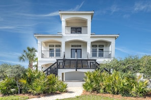 A two-story house with a balcony, a front door, and a staircase leading to the entrance.