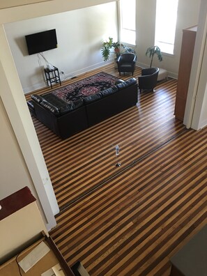 Un ampio soggiorno con un divano in pelle nera, un tappeto decorato e un pavimento in legno.