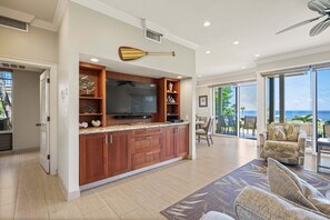 A modern kitchen with a large island, built-in entertainment system, and a view to the outdoors.