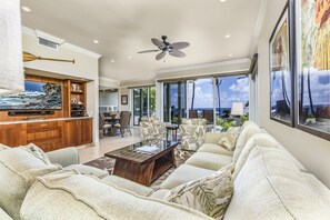 Relax in this spacious living room with a high ceiling and ceiling fan. Enjoy the view from the large window and unwind in the seating area with a sofa and coffee table.