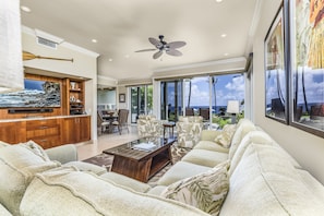 Relax in this spacious living room with a high ceiling and ceiling fan. Enjoy the view from the large window and unwind in the seating area with a sofa and coffee table.