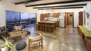 Een moderne keuken met houten kastjes, een centraal eiland en een zithoek met een ronde tafel en stoelen.