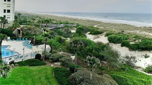 A beachfront hotel with a swimming pool, beach access, and a view of the ocean.