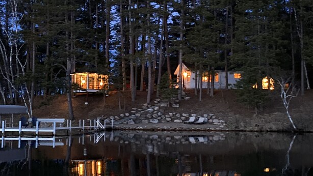 Un conjunto de cabañas junto al lago, con varias construcciones, un muelle y un sendero de piedra.