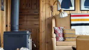 Un salon chaleureux avec un poêle à bois, un fauteuil confortable et un tapis.
