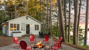 Une cabane avec un foyer et des sièges à l’extérieur.