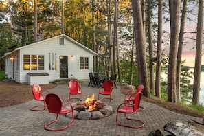 Une cabane avec un foyer et des sièges à l’extérieur.