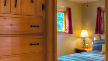 A wooden wardrobe with multiple drawers and a bed with a striped bedspread and a single pillow.