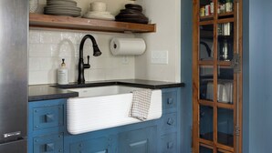 Une cuisine dotée d’un évier encastré, d’étagères en bois et d’un meuble avec des portes en verre.