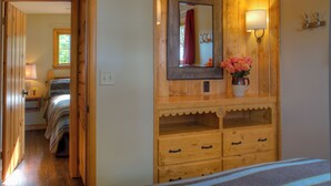 Une commode en bois avec un miroir, un vase de fleurs et une lampe.