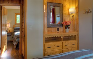 Une commode en bois avec un miroir, un vase de fleurs et une lampe.