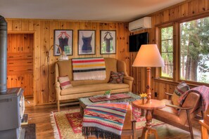 Un acogedor interior de cabaña con detalles de madera, un sofá, una mesa de centro, una lámpara y una chimenea.