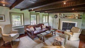 Ein gemütliches Wohnzimmer mit einem braunen Ledersofa, zwei Sesseln, einem Couchtisch und einem Kamin.