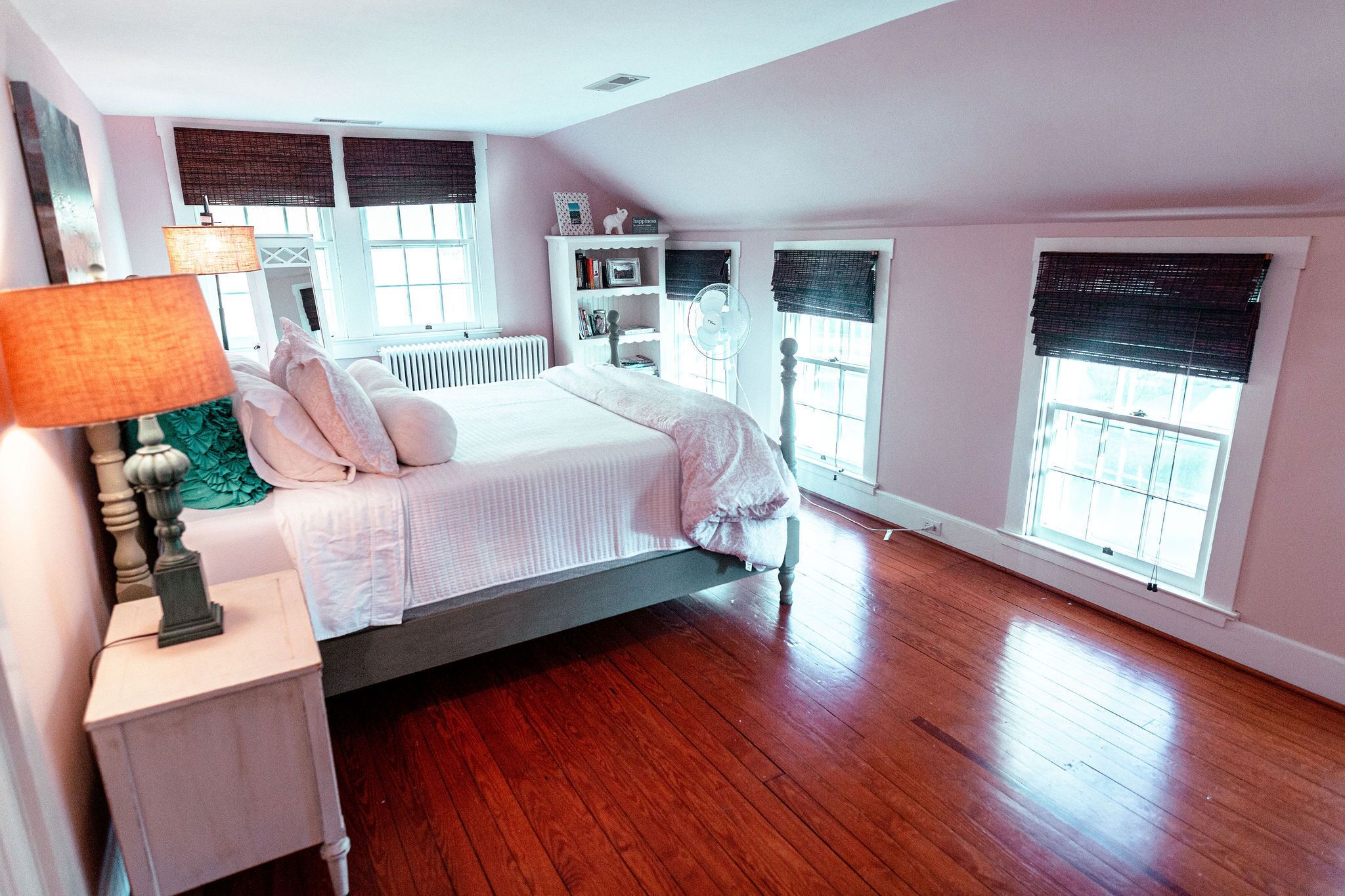 A bedroom with a bed, bedside table, lamp, and a window with blinds.