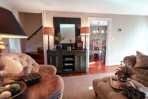 A living room with a wooden coffee table, a sofa, and a dining area in the background.