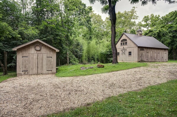 A rustic barn with a gravel driveway leading to a wooden structure.