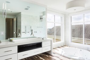 A modern bathroom with a large mirror, white vanity, and a bathtub.