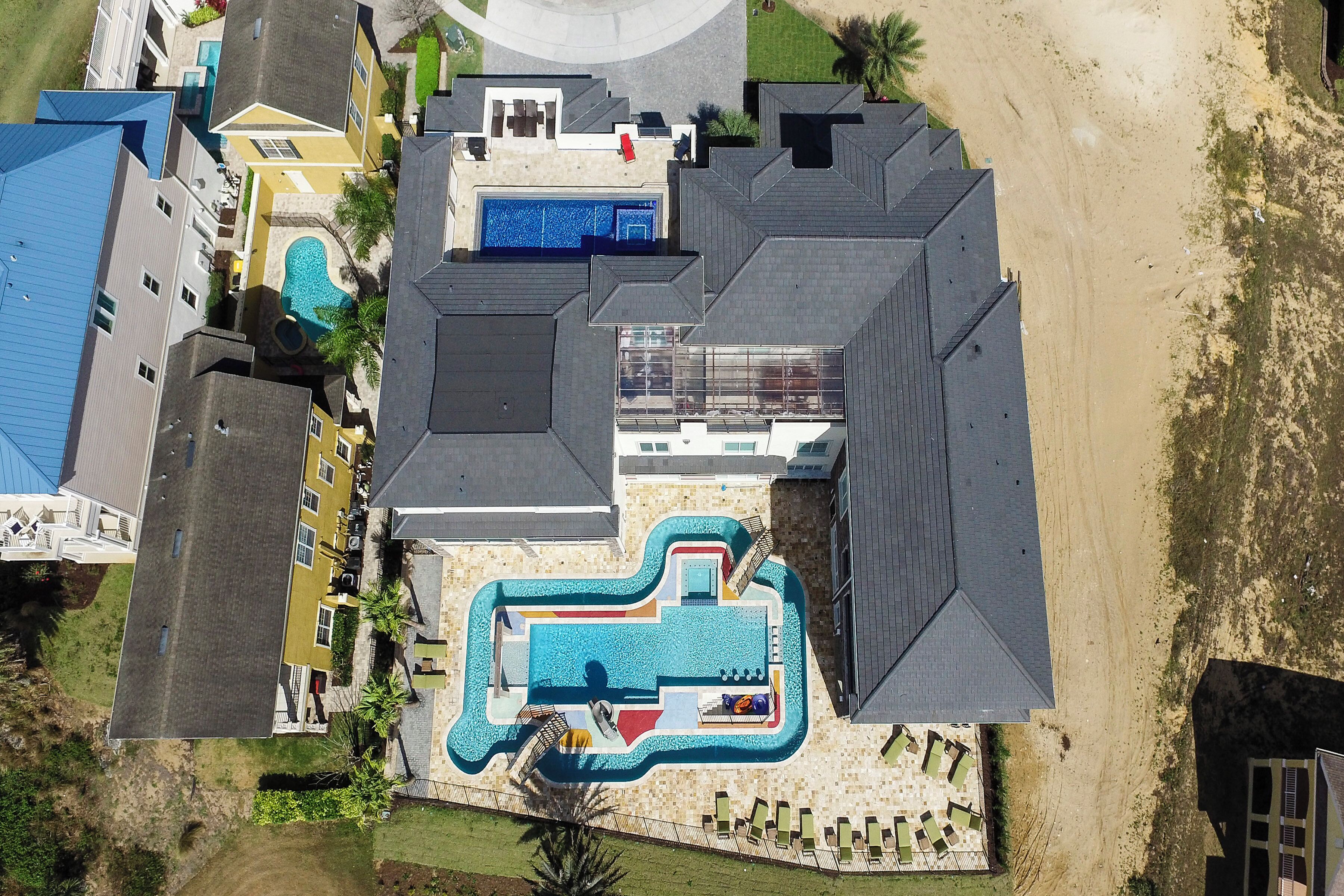 Vue aérienne d’un complexe hôtelier doté d’une grande piscine, de plusieurs bâtiments et d’une plage de sable.