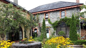 A stone building with a garden featuring yellow flowers and a water feature.