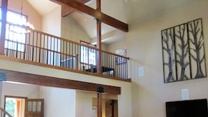 A spacious living area with a large sectional sofa, a ceiling fan, and a flat-screen TV mounted on the wall.