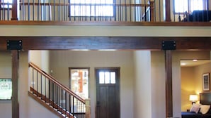 A spacious living area with a large sectional sofa, two black ottomans, and a staircase leading to an upper level.