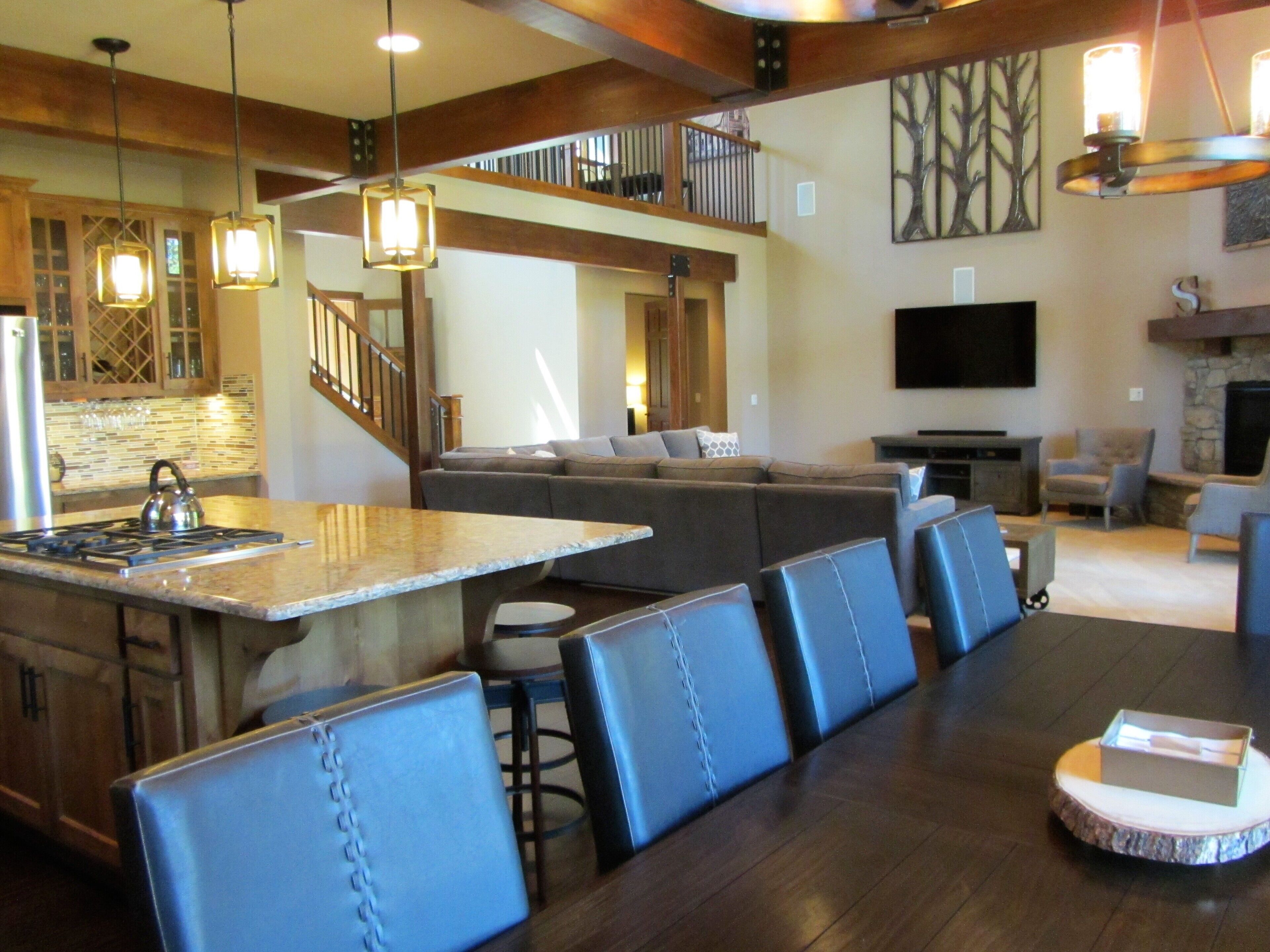 A spacious living area with a large island, leather seating, a fireplace, and a television.