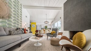Ein modernes Wohnzimmer mit einer Couch, Sesseln, einem Couchtisch und einem Kamin.