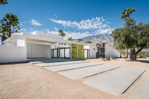 Un bâtiment moderne doté d’un toit plat, d’une clôture verte et ayant une chaîne de montagnes en toile de fond.