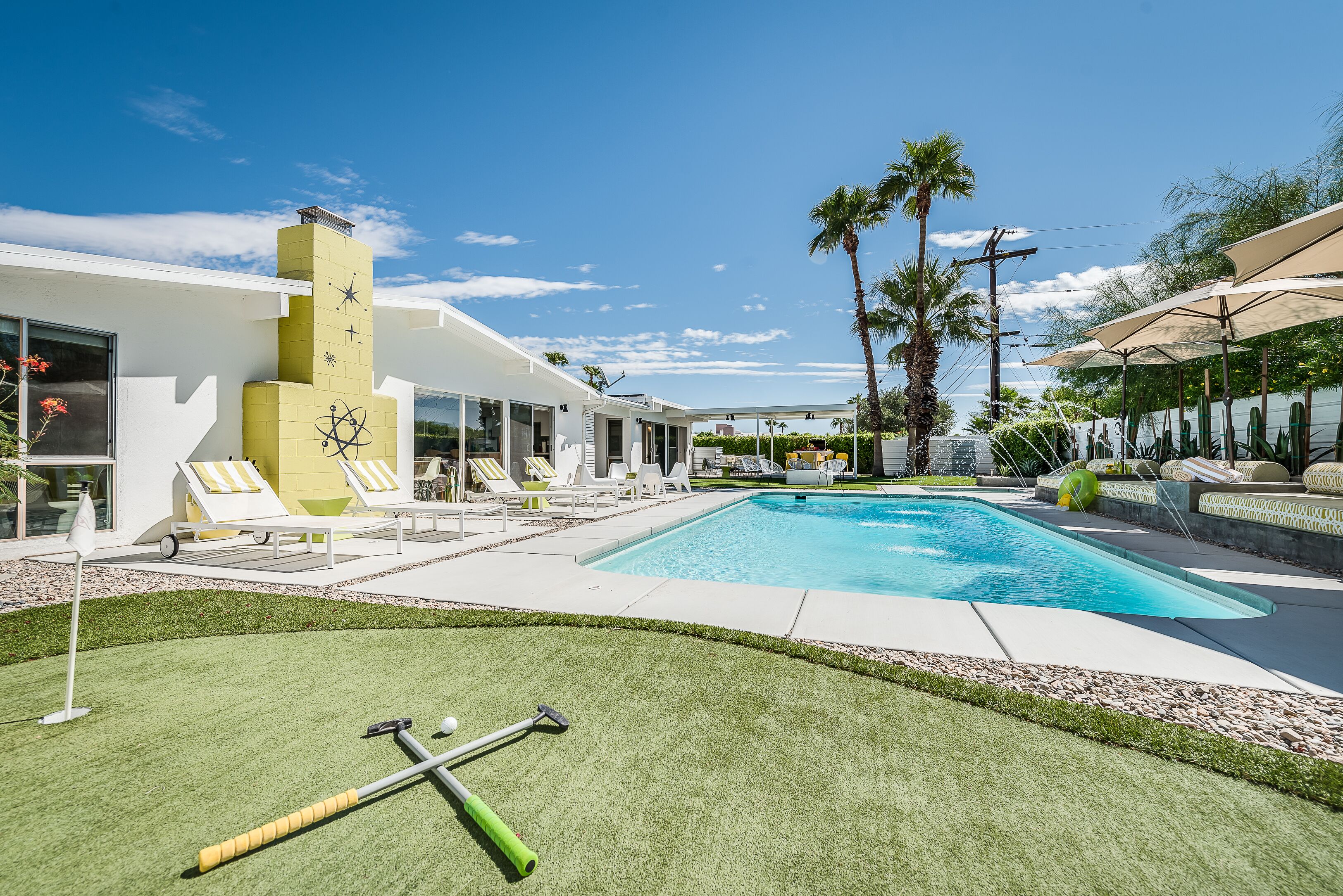 Un'area piscina moderna con una piscina azzurra e cristallina, lettini e un prato ben curato.