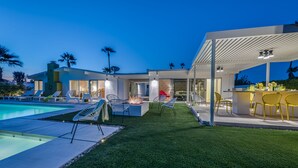Ein modernes Haus mit Swimmingpool, Sitzgelegenheiten im Freien und einer überdachten Terrasse.