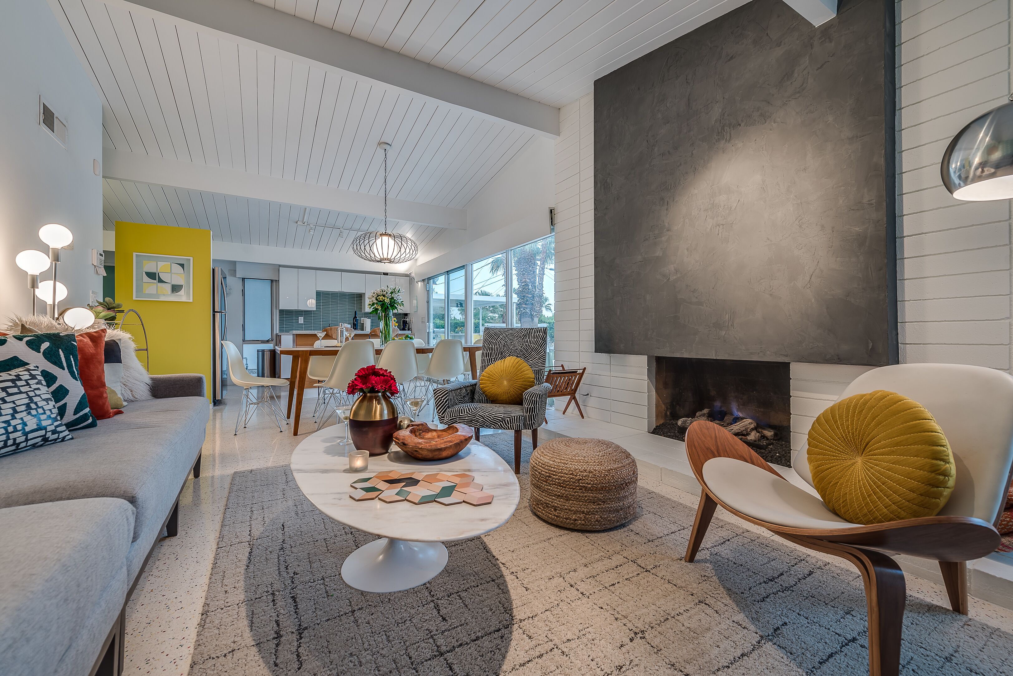 A spacious living room with a fireplace, a dining area, and a kitchen in the background.
