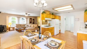 A spacious living area with a dining table set for four, a kitchen with wooden cabinets, and a ceiling fan. - Riverside Manna, "Gateway to Beautiful Yosemite Valley" Modern 3bd/2 ba cottage (Mariposa)