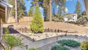 A backyard with a wooden fence, a large tree, and a house in the background. - Riverside Manna, "Gateway to Beautiful Yosemite Valley" Modern 3bd/2 ba cottage (Mariposa)