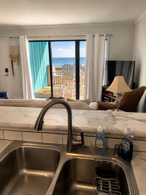 Eine Küche mit Spüle, Fernseher und Blick auf den Strand.