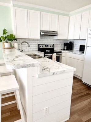 A kitchen with white cabinetry, a marble countertop, a stainless steel range, and a built-in oven. - Oceanfront 2BR/2BA Pet-Friendly _ POOL!_ Walk to Boardwalk_ Private Beach Access (Carolina Beach)