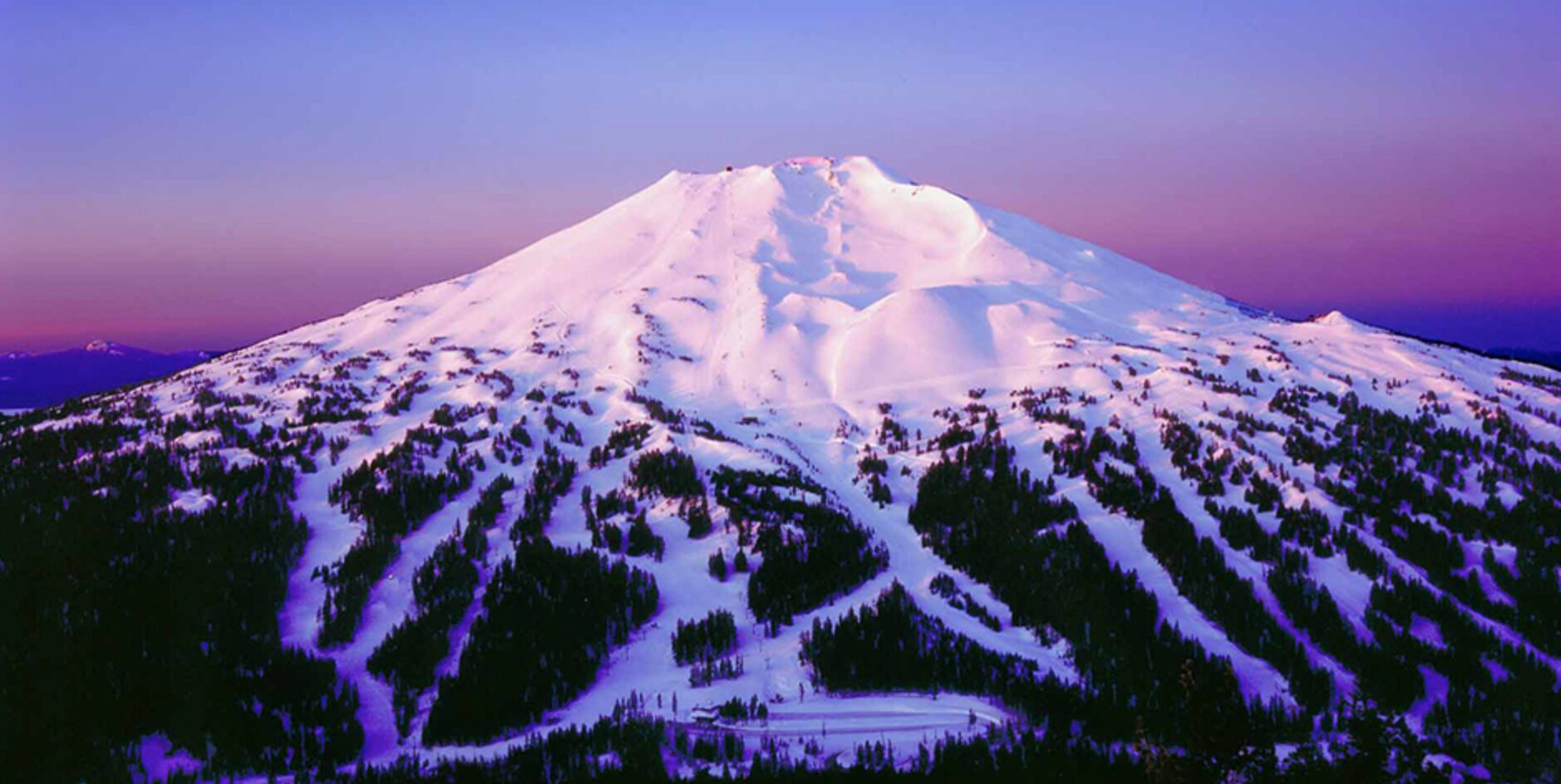 Une montagne enneigée, avec une station de ski à ses pieds.