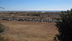 A dry, open landscape with a stone wall in the foreground and a clear blue sky. - 405 Captain John Fripp Villa - Ocean Front - Ground Level (Fripp Island)