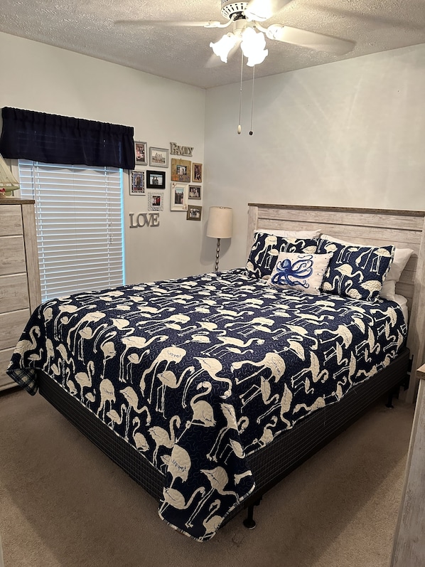 A bedroom with a bed, a ceiling fan, a window with blinds, and wall decorations.