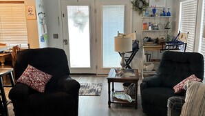 A living room with two armchairs, a coffee table, a bookshelf, and a dining area with a table and chairs. - 2 Bedroom / 2 Bath - Close to Everything! (Myrtle Beach)