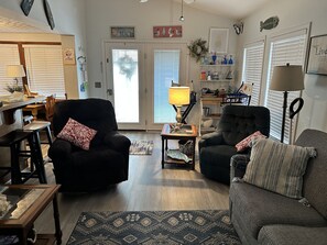 A living room with two black armchairs, a wooden coffee table, and a patterned rug.