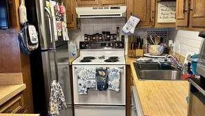 A compact kitchen with wooden cabinets, a stainless steel refrigerator, a white stove, and a granite countertop. - 2 Bedroom / 2 Bath - Close to Everything! (Myrtle Beach)