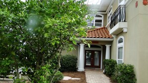 A house with a tiled roof, a front porch, and a pathway leading to the entrance. - Resort Home, 6 Bedrms,4.5bath, pool,Pet friendly, on Gulf,Gated (Panama City Beach)