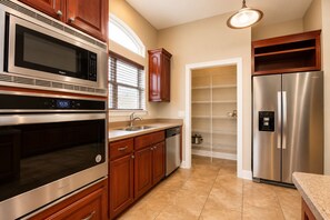 A kitchen with stainless steel appliances, wooden cabinets, a built-in oven, and a refrigerator with a water dispenser. - Resort Home, 6 Bedrms,4.5bath, pool,Pet friendly, on Gulf,Gated (Panama City Beach)