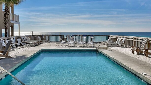 A rectangular pool with a clear blue water surface, surrounded by lounge chairs and a wooden fence. - Resort Home, 6 Bedrms,4.5bath, pool,Pet friendly, on Gulf,Gated (Panama City Beach)