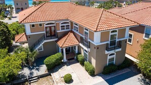A multi-story residential building with a red-tiled roof, a central entrance with a staircase, and a view of the ocean. - Resort Home, 6 Bedrms,4.5bath, pool,Pet friendly, on Gulf,Gated (Panama City Beach)