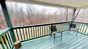 A covered outdoor deck with two metal chairs and a wooden stump. - Spacious Bobcat Cabin, 30 mins from Hocking Hills (Nelsonville)