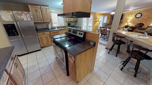 A kitchen with wooden cabinets, a stainless steel refrigerator, a black stove, and a wooden island with a sink. - Spacious Bobcat Cabin, 30 mins from Hocking Hills (Nelsonville)